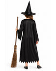 A child shown from the back wearing a black witch costume with a pointed black hat and holding a brown broom against a plain white studio background.