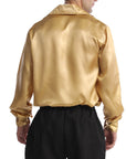A man wearing a shiny gold satin long-sleeve shirt and black pants, shown from the back against a plain white background.