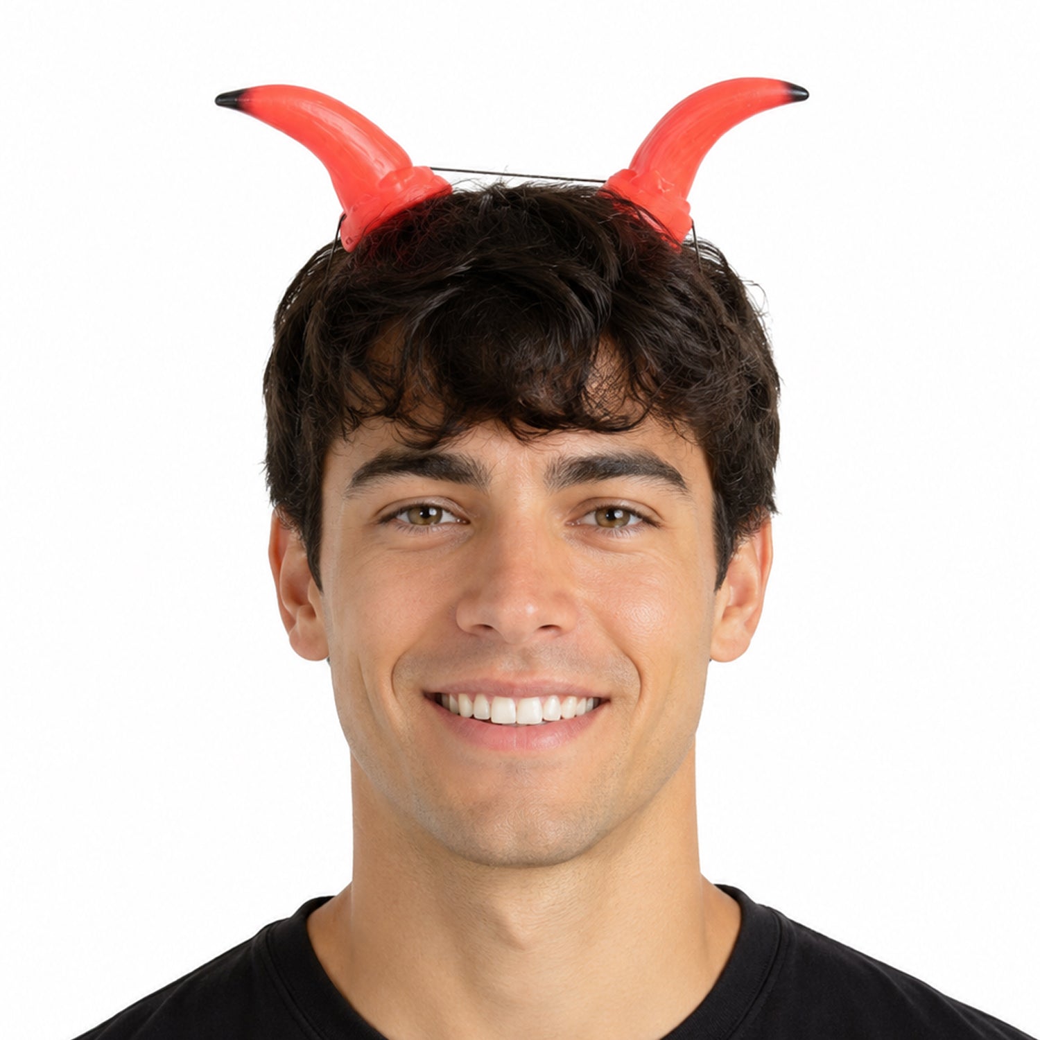 A smiling man wearing a pair of red devil horns with black tips on a white background.