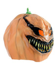 A novelty Halloween pumpkin mask with a menacing, wide grin, glowing orange eyes, and sharp yellow teeth, featuring a small green stem on top, isolated on a white background.