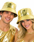 A man and a woman wearing shiny metallic gold bucket hats and matching gold outfits, smiling against a plain white background.