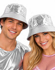 A man and a woman wearing shiny silver bucket hats and matching metallic silver tops, smiling against a plain white background.