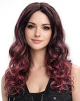 Woman with long, wavy, purple hair wearing a black sleeveless top on a white background