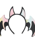 A bat-themed headband featuring two black bat wings with iridescent pastel pink, yellow, and blue edges, and two black bat ears on a white background.