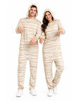 A man and a woman modelling matching hooded one-piece jumpsuit with beige and white horizontal stripes like bandages, posed against a plain white studio background.