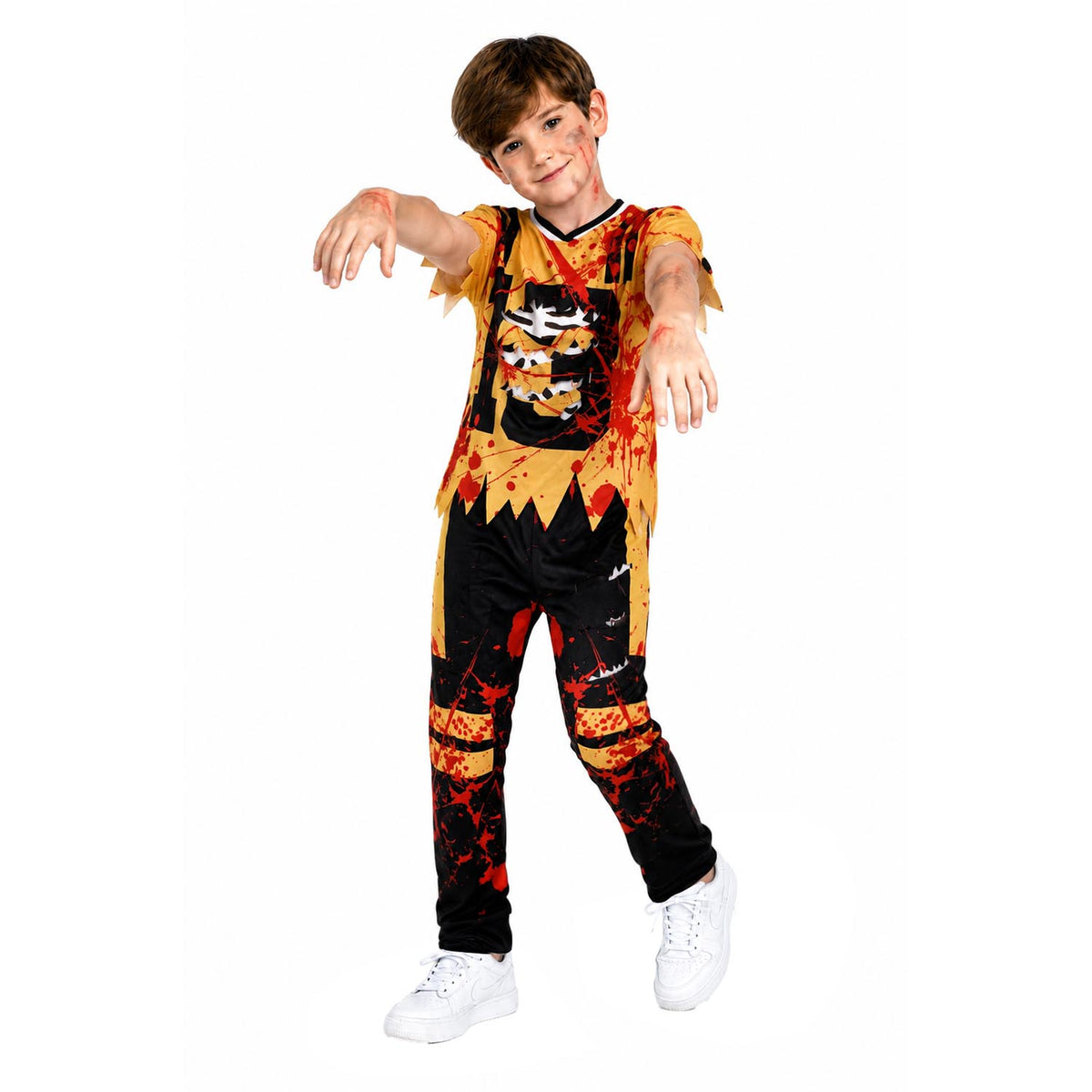A child modeling a zombie-themed Halloween costume consisting of a short-sleeve top and matching pants with a distressed black and orange print, blood splatter details, and a zombie face graphic on the chest, paired with white sneakers against a plain white background.