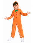 A child wearing an orange gingerbread man costume jumpsuit with white piping, red buttons, and a green bow tie, standing against a plain white background.