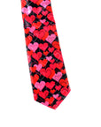 A necktie featuring a dense pattern of overlapping hearts in red, pink, and hot pink on a black background, isolated on a white studio background.